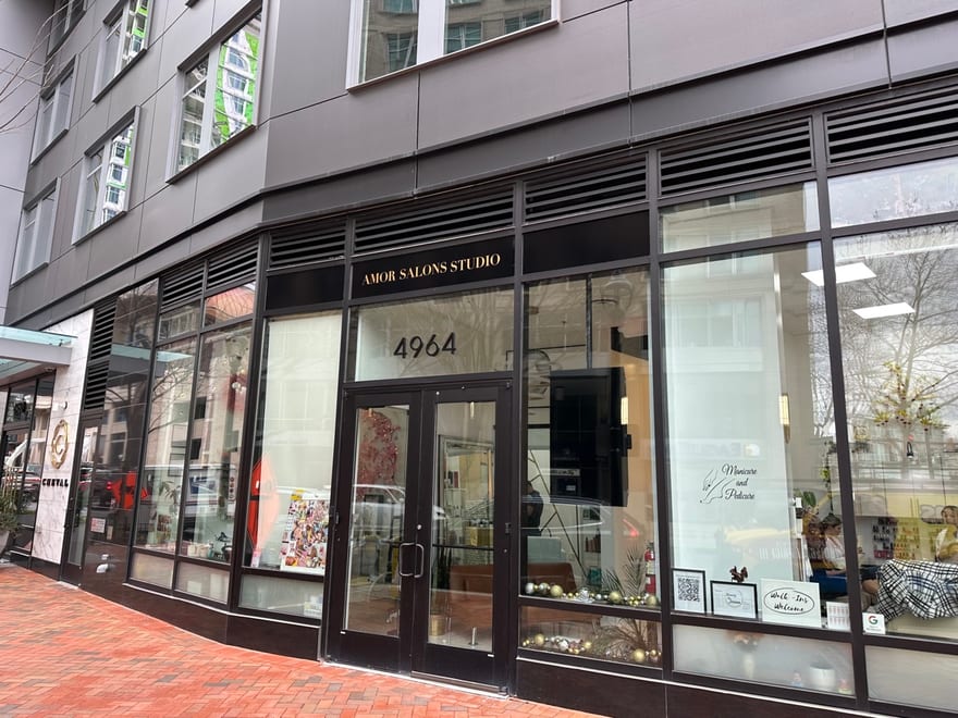 The Amor Studio Salons shopfront at 4964 Fairmont Avenue, Bethesda: a dark glazed frontage under an awning, with the gold lettering on the granite pier beside the door.