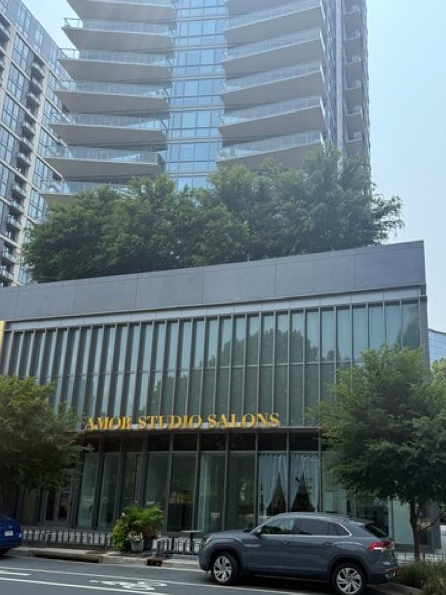 The Amor Studio Salons name in gold lettering across the glazed podium at 7917-B Westpark Drive, with a Tysons residential tower rising directly above it.